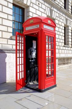 a red phone booth sitting on the side of a building