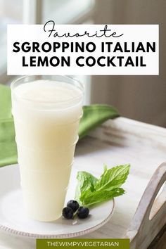 a glass of lemonade sitting on top of a white plate next to a green leaf