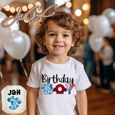 a young child standing in front of balloons with the words birthday boy printed on it