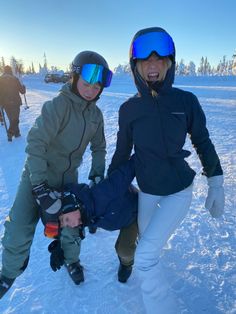 two people on skis in the snow with one person holding another's leg