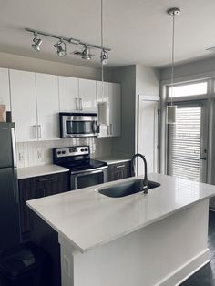 an empty kitchen with stainless steel appliances and white countertops