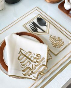 a white and gold place setting with silverware, napkins, and utensils