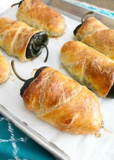 several hot dogs wrapped in croissants and stuffed with peppers on a baking sheet