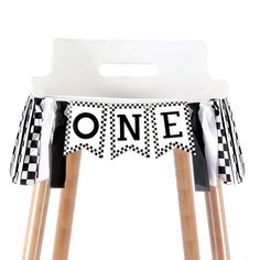 a black and white one sign sitting on top of a wooden stool with two legs