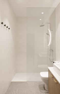 a bathroom with a toilet, sink and shower head mounted to the side of the wall