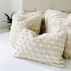 two white pillows sitting on top of a bed next to a plant in a pot