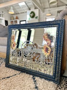 a mirror sitting on top of a rug in front of a couch with sunflowers