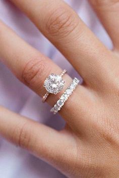 a woman's hand with two engagement rings on it