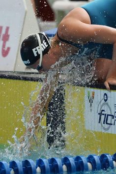 a woman is diving into the pool with her head in the water while wearing a swimming cap