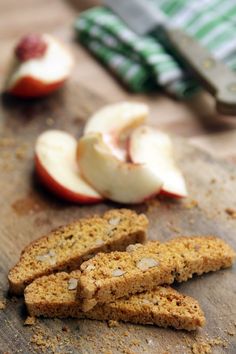 sliced apples on a cutting board next to knifes and other food items in the background