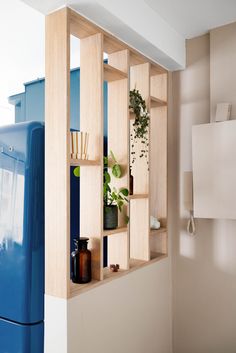 a blue refrigerator freezer sitting inside of a kitchen next to a wooden shelf filled with plants