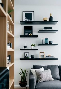 a living room filled with lots of shelves next to a gray couch and potted plant