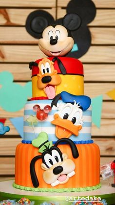 a mickey mouse birthday cake with goofy and pluto on it's top tiers