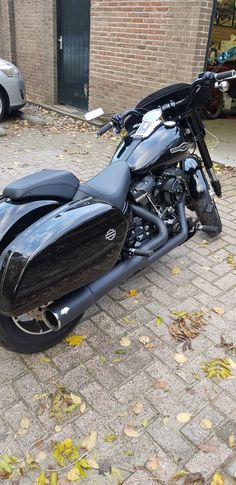 a black motorcycle parked on top of a brick road