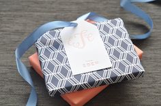 a small gift box with a blue ribbon tied around it and a tag on top