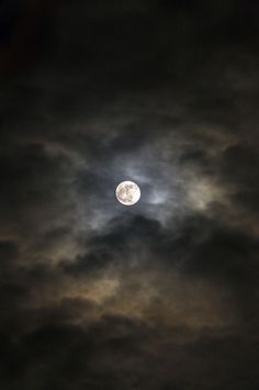 the moon is shining brightly in the cloudy sky