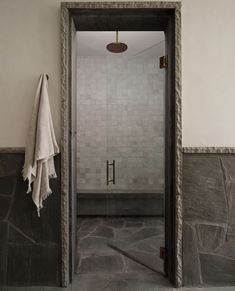 an open door leading into a bathroom with stone walls and flooring, along with a white towel hanging on the wall