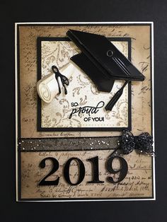 a graduation card with a graduate cap and diploma on it's side, hanging from a black frame