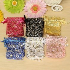 several different colored bags sitting on top of a wooden table with flowers in the background