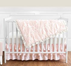 a white crib with pink and gold bedding on it's bottom rail