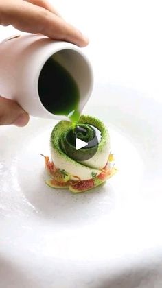 someone is pouring green liquid into a small pastry