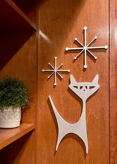 three metal snowflakes are on the wall next to a potted plant