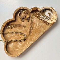 a heart shaped tray with gold jewelry on it