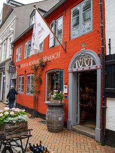 an orange brick building with white trim and flowers on the outside, in front of it