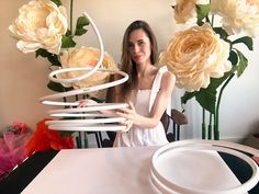 a woman standing in front of a white table with flowers on it and some plates