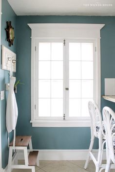 a room with blue walls and white furniture in it, along with a large window