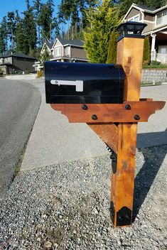 a mailbox sitting on the side of a road next to a street with houses in the background