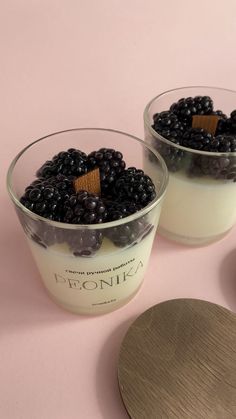 two glasses of yogurt with blueberries in them on a pink tablecloth