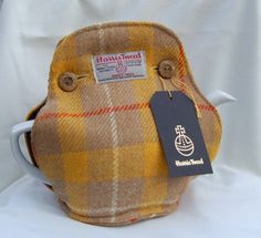 a brown and yellow plaid bag with a tag on it's side, sitting on a white surface