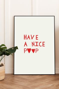 a poster with the words have a nice poop in red on it next to a potted plant