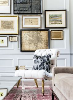 a living room filled with lots of framed pictures on the wall above a white couch