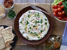 hummus and pita chips on a table with tomatoes, celery, green beans