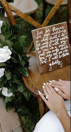 a woman sitting in a chair with white nails on her hand and a wooden sign that says, i am married