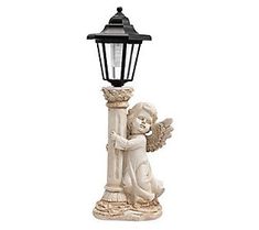 a lamp post with an angel holding a bird on it's arm and sitting next to a street light