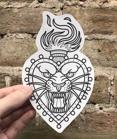 a hand holding up a sticker with an image of a tiger's head