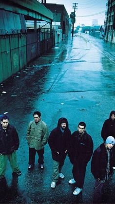 five young men standing in the middle of an alleyway, one wearing a hoodie