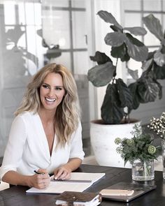 a woman sitting at a table with a notebook and pen in front of her on instagram