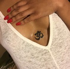 a woman's chest with an omen symbol tattoo on her left shoulder and red nails