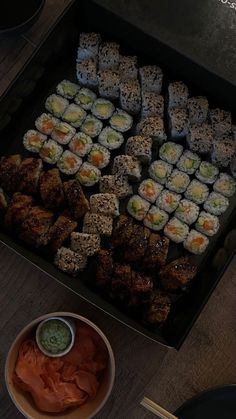 there are many sushi and sauces in the tray on the table next to each other