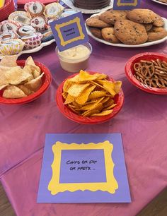 a table topped with plates and bowls filled with food next to a sign that says chips or crackers