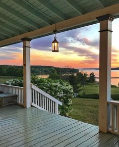 a porch with a light hanging from it's ceiling and a view of the water