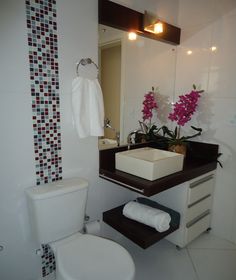 a white toilet sitting next to a sink in a bathroom under a mirror with pink flowers on it