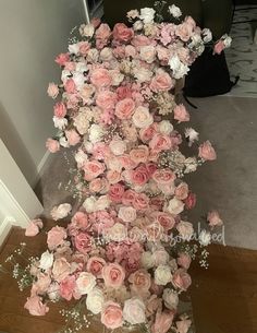 a vase filled with pink and white flowers on top of a wooden floor next to a doorway