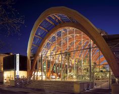 the entrance to a building lit up at night with large glass windows on each side