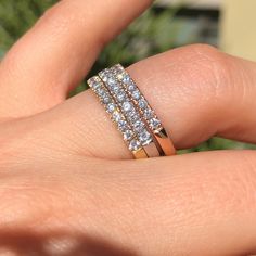 a woman's hand holding a three row diamond ring on top of her finger