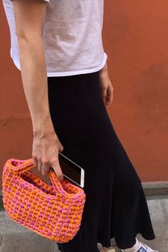 a woman holding a cell phone in her hand while standing next to a brown wall